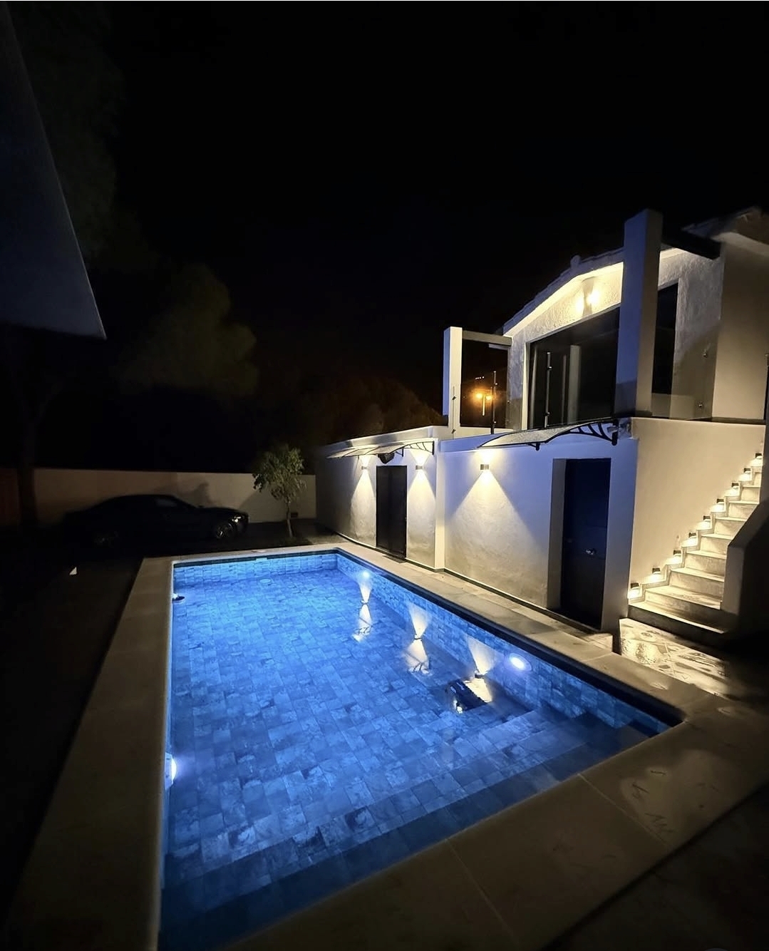 Piscina privada iluminada de La Maison VIP Club por la noche